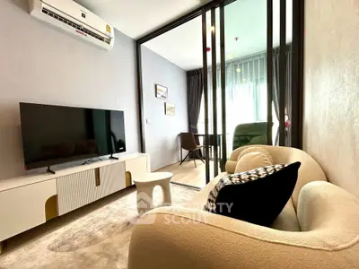 Modern living room with stylish furniture and large TV in a cozy apartment setting.
