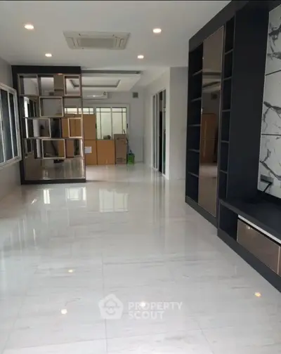 Spacious modern living room with sleek marble flooring and built-in shelving.