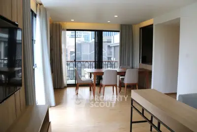 Modern living room with large windows and stylish dining area in a city apartment.