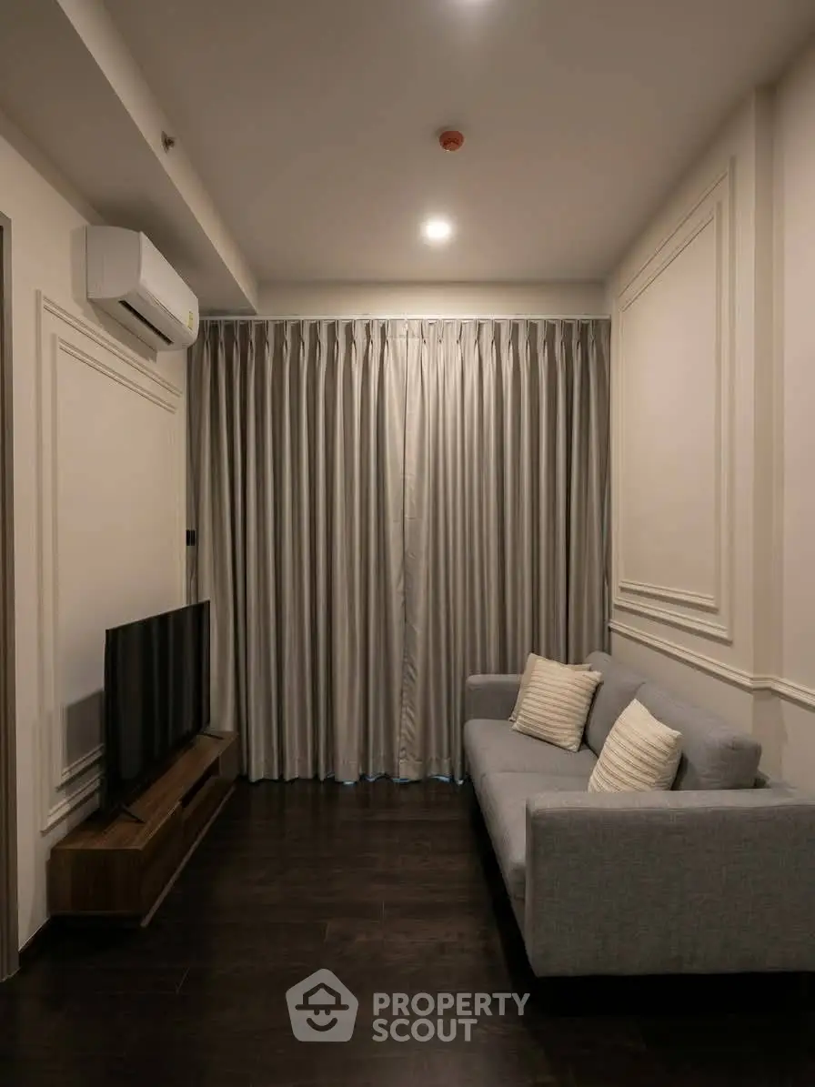 Cozy living room with modern sofa and TV, featuring elegant curtains and air conditioning.