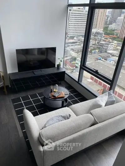 Modern living room with city view, featuring sleek furniture and large windows.