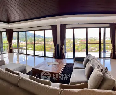 Luxurious living room with panoramic windows and stunning view, featuring elegant furniture and spacious design.