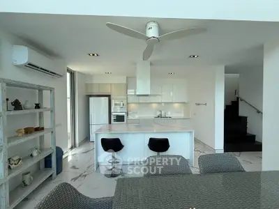 Modern open-layout kitchen with sleek white cabinetry, island seating, and integrated appliances in a bright, airy space.
