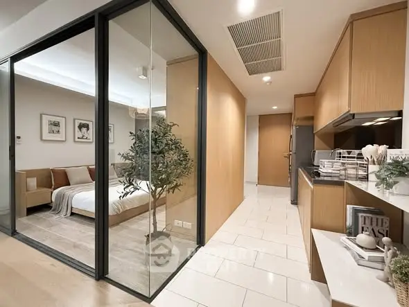Modern apartment interior with glass-walled bedroom and sleek kitchen design.
