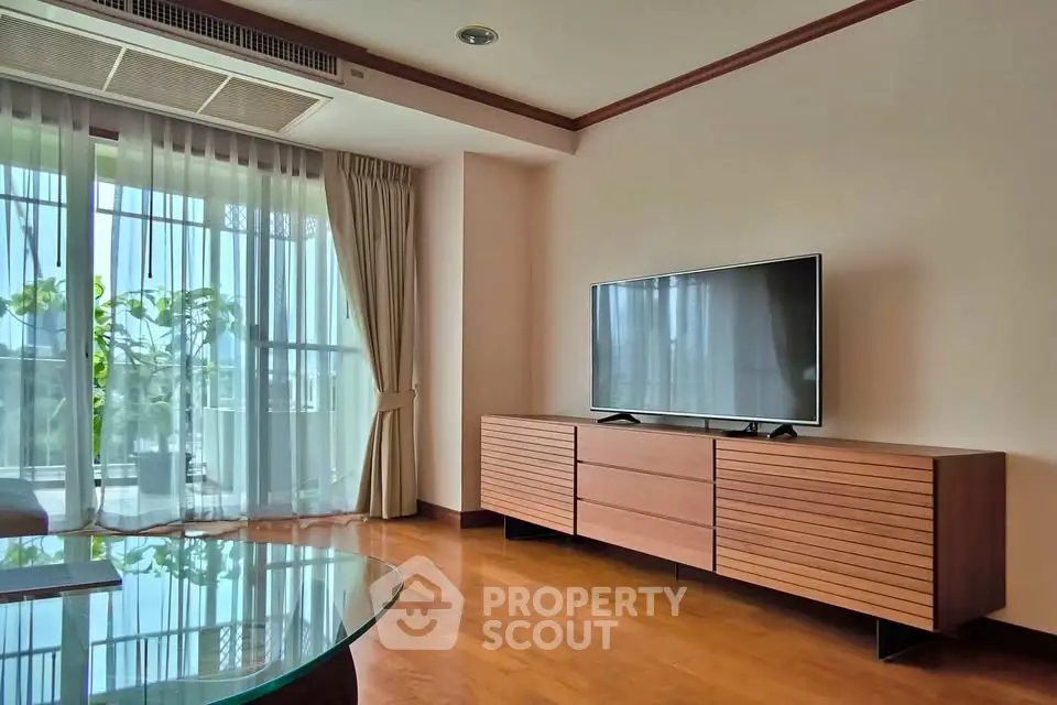 Spacious living room with modern TV setup and large window view