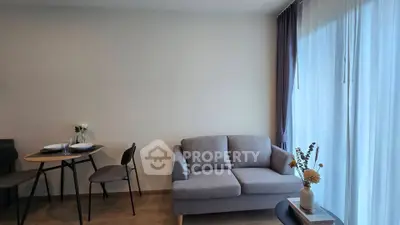 Modern living room with cozy sofa and dining area, featuring elegant decor and natural light.