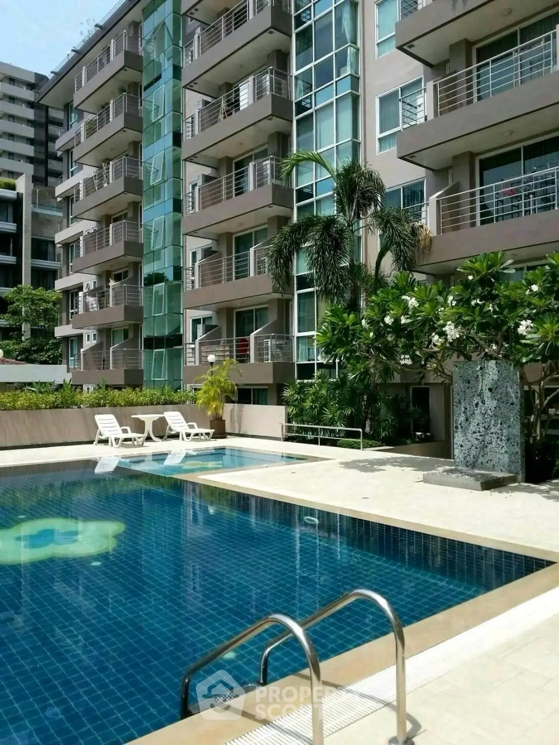 Luxurious apartment building with a stunning pool and lush greenery, perfect for modern living.