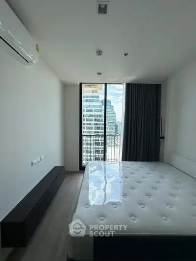 Modern bedroom with large window offering stunning city view in high-rise apartment.