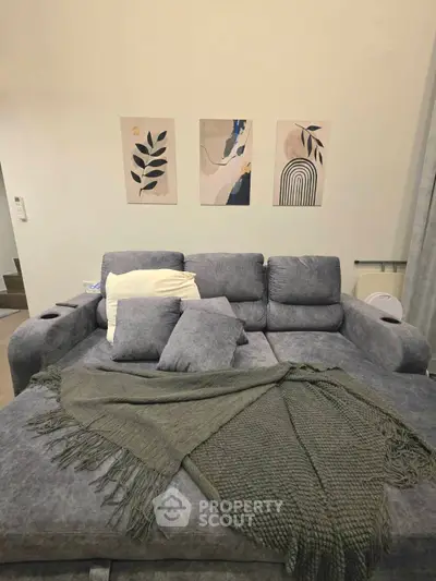 Cozy living room with stylish gray sofa and modern art decor, perfect for relaxation.