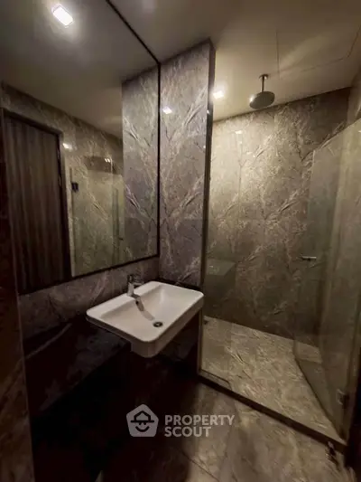 Luxurious modern bathroom with sleek marble design and glass shower enclosure.