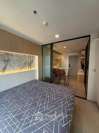 Modern bedroom with stylish decor and open layout leading to kitchen area.