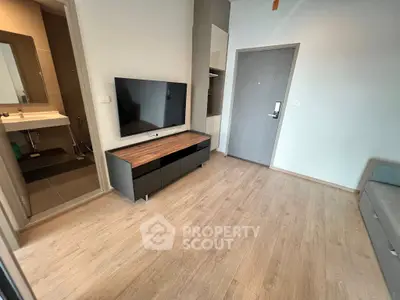 Modern living room with wooden flooring and wall-mounted TV in a stylish apartment.