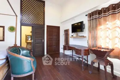 Charming vintage-style living room with wooden floors, elegant furniture, and wall-mounted TV, perfect for cozy relaxation.