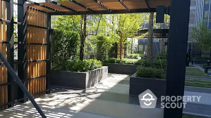 Modern garden area with pergola and lush greenery in urban residential complex.