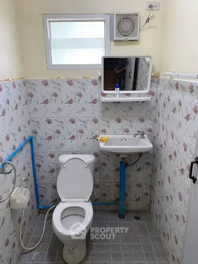 Compact bathroom with floral tiles and basic fixtures