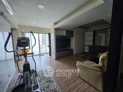 Spacious living room with exercise equipment and modern decor, featuring large windows for natural light.