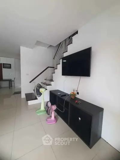 Modern living room with sleek staircase and wall-mounted TV