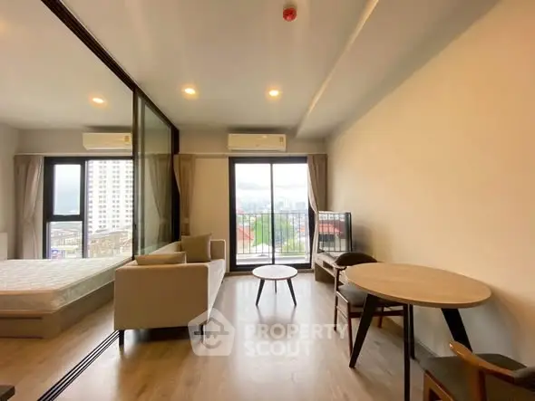 Modern studio apartment with balcony and city view, featuring open layout and stylish furnishings.