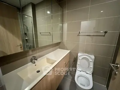 Modern bathroom with sleek fixtures and large mirror in contemporary apartment.