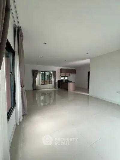 Spacious open-plan living room with modern kitchen and large windows for natural light.