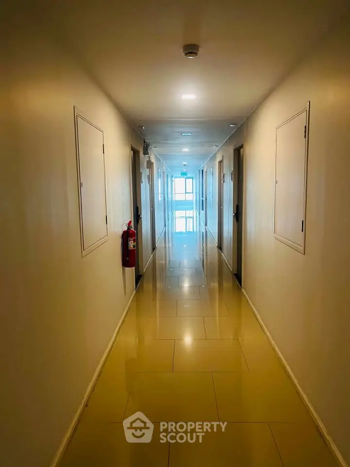 Bright and spacious corridor with polished floors leading to a window with natural light.