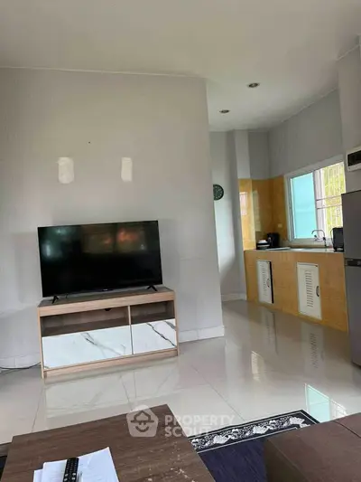 Modern living room with TV and adjacent kitchen area, sleek design and bright ambiance.