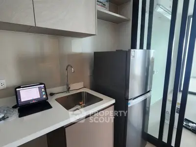 Modern kitchen with sleek design featuring stainless steel fridge and compact workspace.