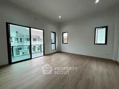 Spacious empty room with large windows and wooden flooring in modern home