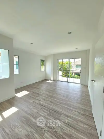 Spacious empty room with large windows and wooden flooring, perfect for customization.