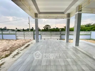 Spacious covered patio with tiled flooring and scenic view of greenery.