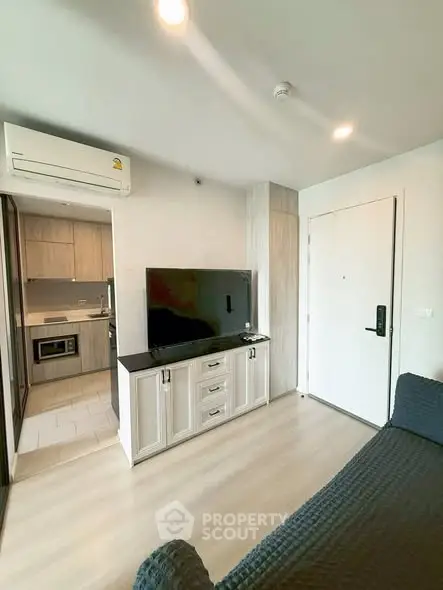 Modern living room with sleek TV setup and view into a stylish kitchen
