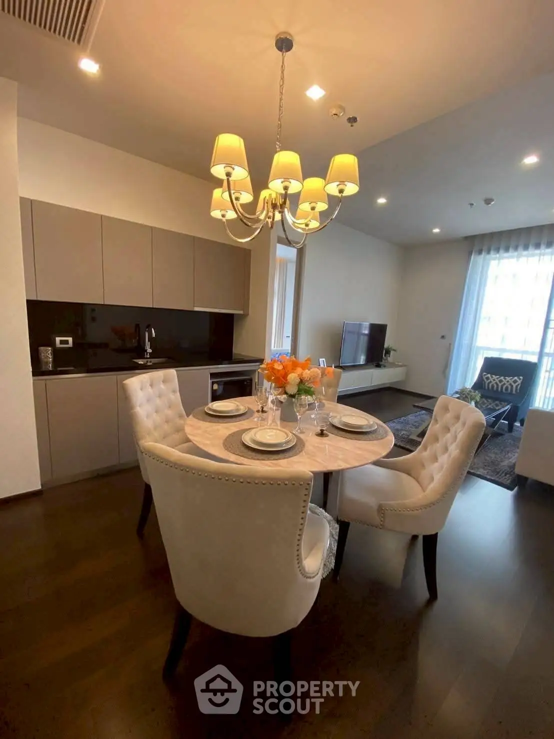 Elegant dining area in modern apartment with stylish chandelier and cozy seating.