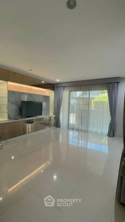 Spacious modern living room with large windows and elegant curtains