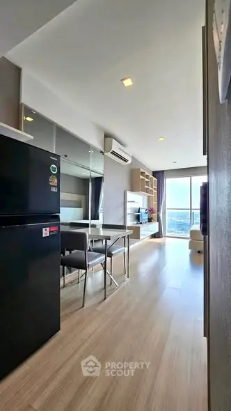 Modern open-plan living room with sleek kitchen and large windows offering city views.