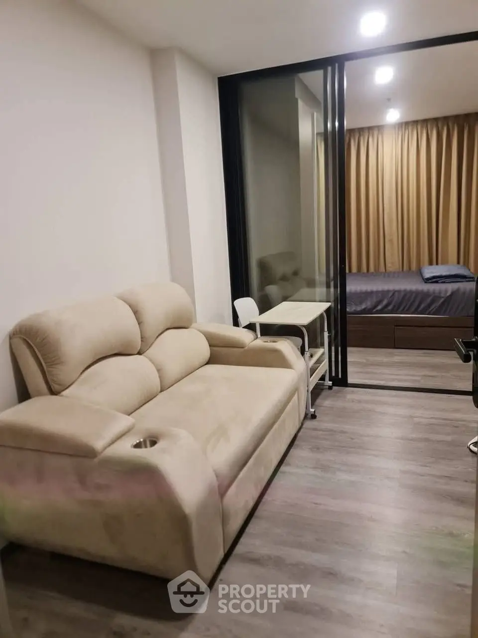 Modern studio apartment with cozy living area and bedroom separated by glass partition.