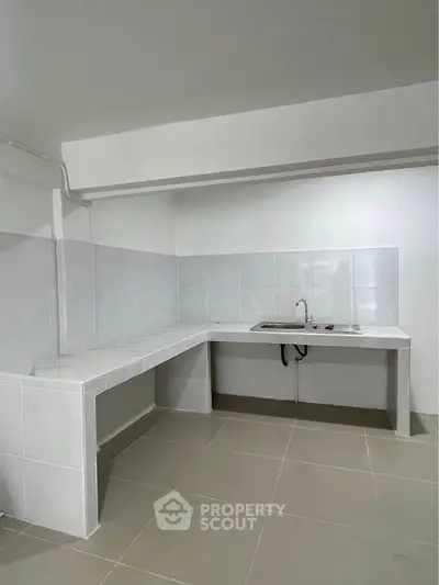 Minimalist kitchen with white tiled countertops and sink, perfect for compact spaces.