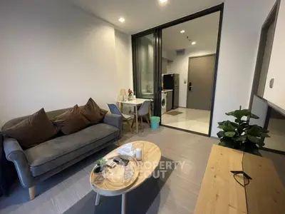 Modern living room with cozy seating and open kitchen layout in stylish apartment.