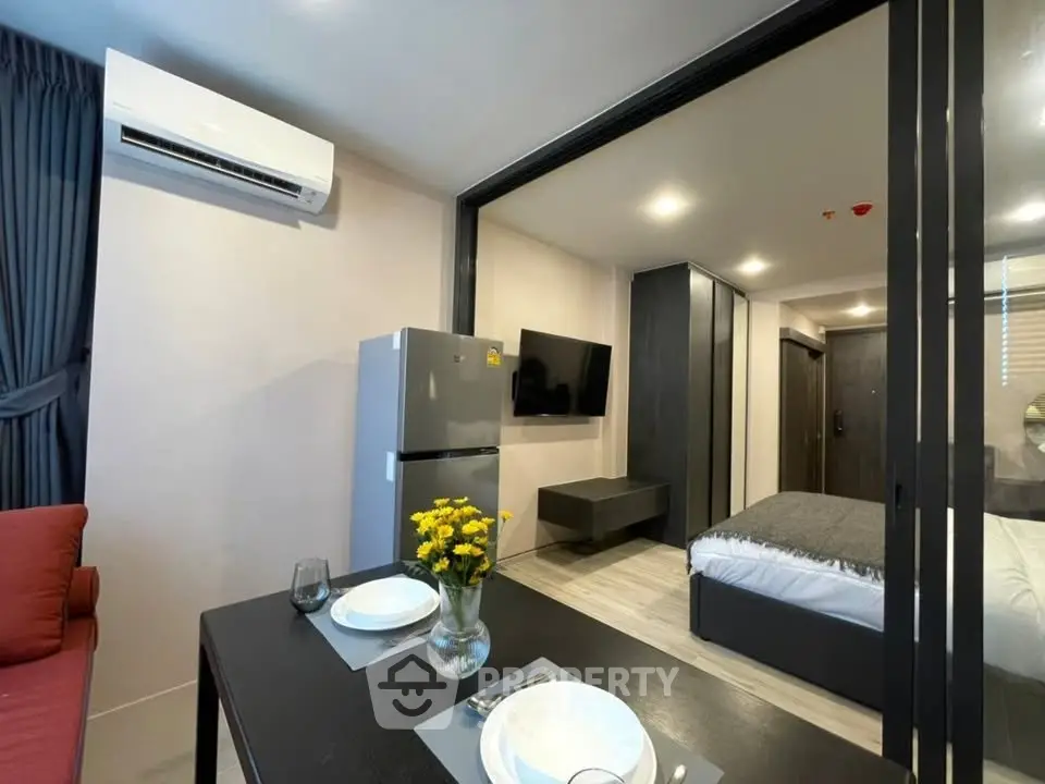 Modern studio apartment with sleek design, featuring a cozy living area, dining space, and compact kitchen.