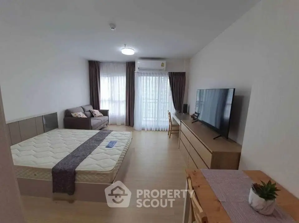 Spacious modern bedroom with large window, cozy sofa, and sleek TV setup.