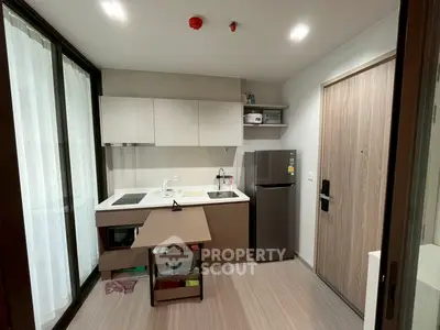 Modern compact kitchen with sleek cabinetry and stainless steel fridge in a stylish apartment.