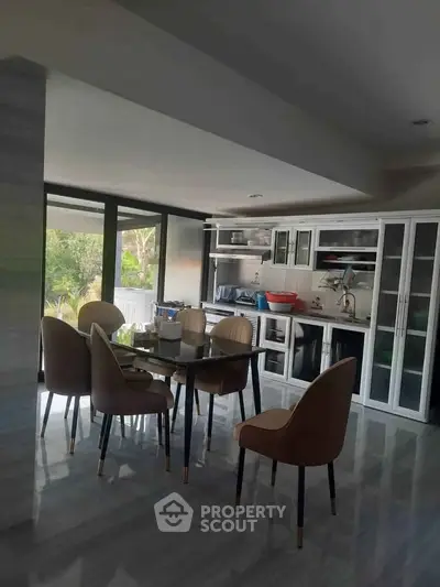 Modern kitchen with dining area, sleek cabinetry, and garden view, perfect for family gatherings.
