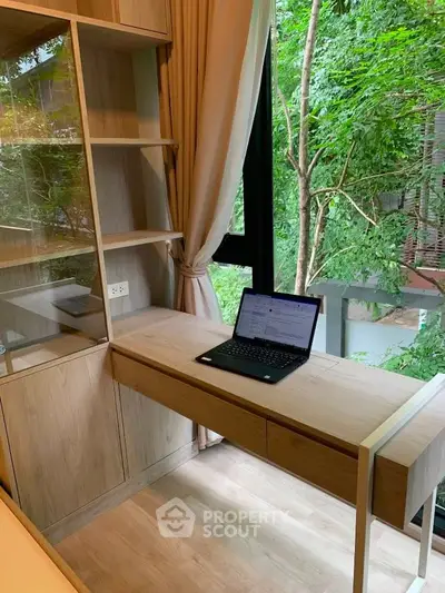 Modern study nook with wooden desk and lush green view through window.