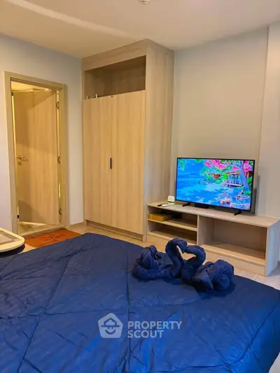 Cozy bedroom with modern wardrobe and TV, featuring elegant swan towel decor on the bed.