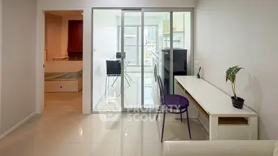 Modern apartment interior with sleek design and glass partition, featuring a cozy workspace and city view.