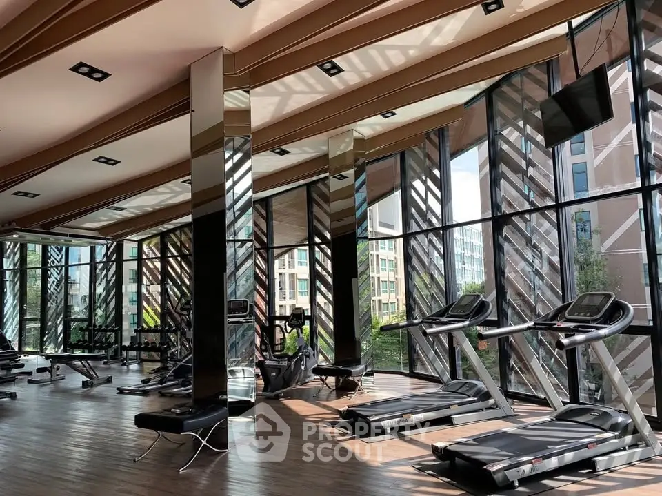 Luxurious gym with modern equipment and floor-to-ceiling windows offering stunning views.