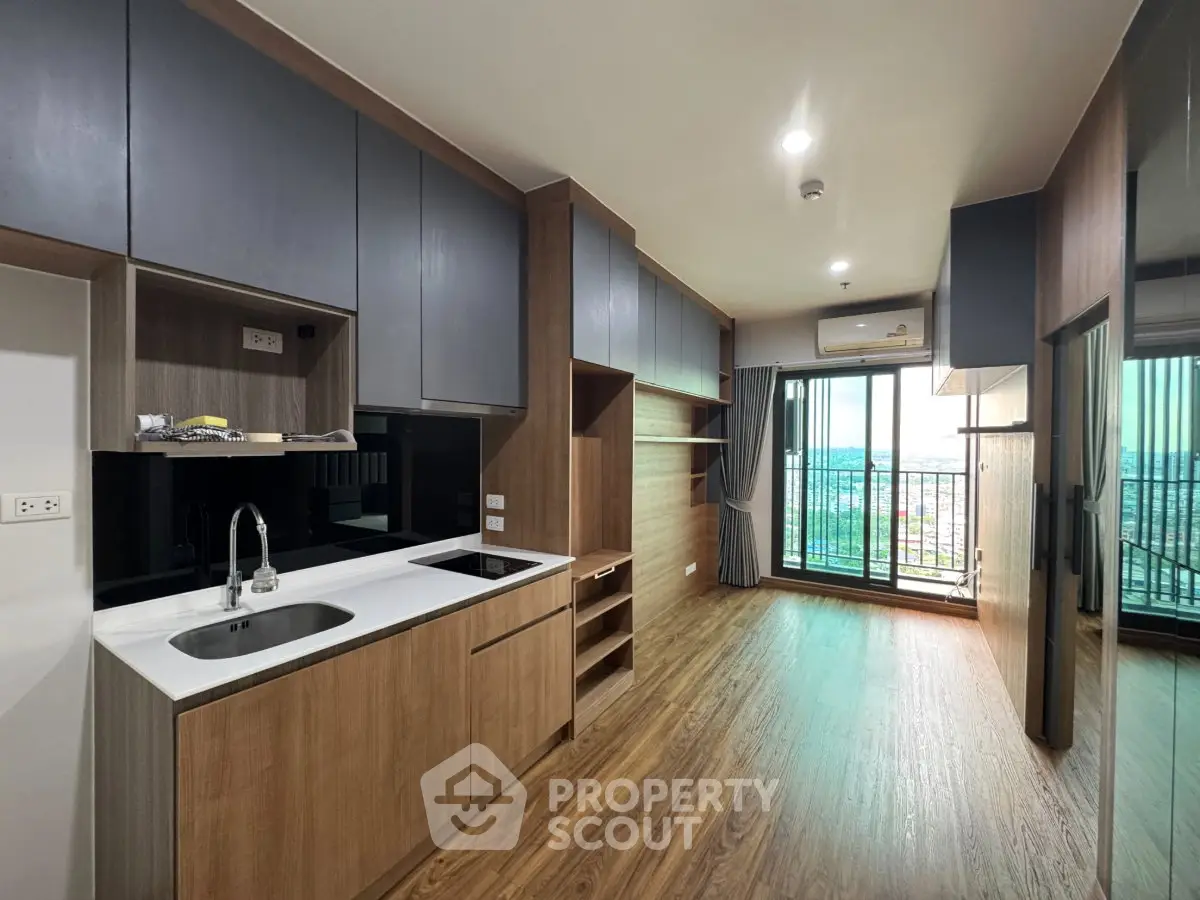 Modern kitchen with sleek cabinetry and open layout leading to a balcony with city view.