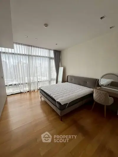 Spacious bedroom with large window and modern furniture in a luxury apartment.