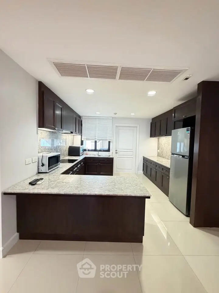 Spacious modern kitchen with granite countertops and stainless steel appliances.