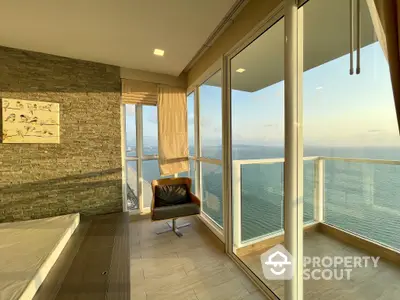 Luxurious corner unit with floor-to-ceiling windows offering panoramic sea views, accented by a stone feature wall and modern furnishings.