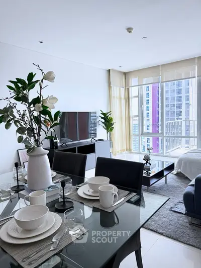 Modern living room with dining area and large windows offering city views, featuring elegant decor and natural light.